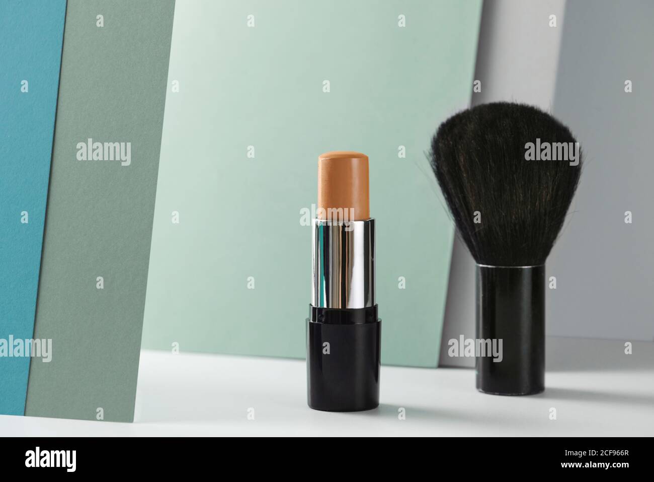 Concealer stick and make up brush on modern background Stock Photo