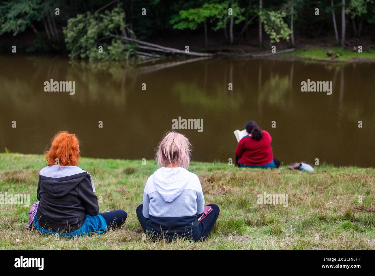Chilling and reading a book by the lake at We Are Not a Festival socially distanced event in Pippingford Park - camping with a festival vibe Stock Photo