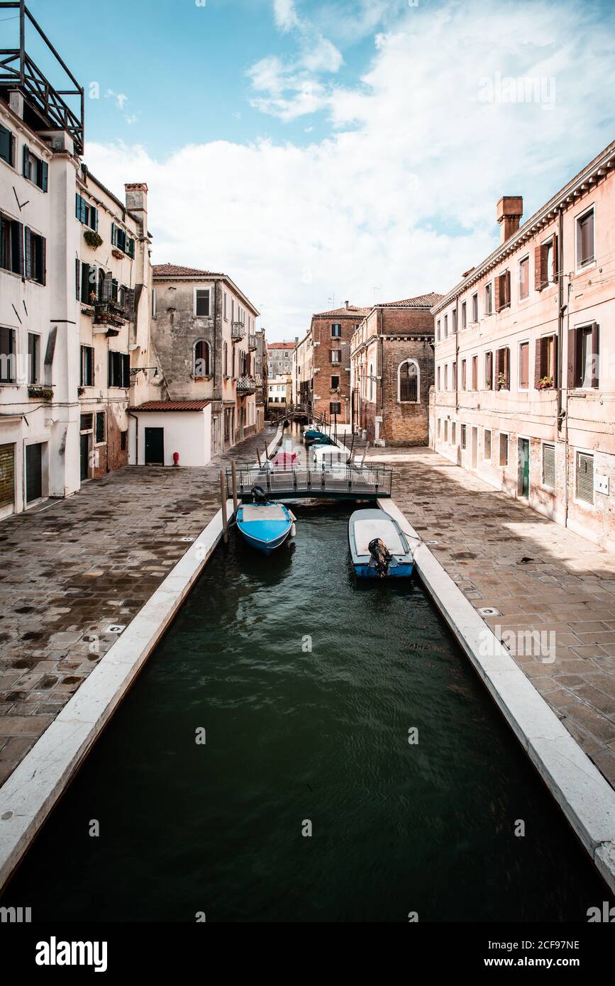Narrow canal with boats in Venice Italy Stock Photo