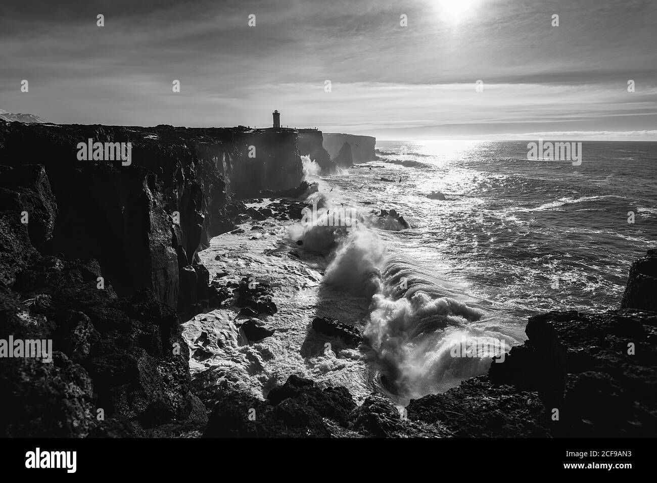 Storm waves at the west coast of Iceland and Svörtuloft Lighthouse at the distance Stock Photo