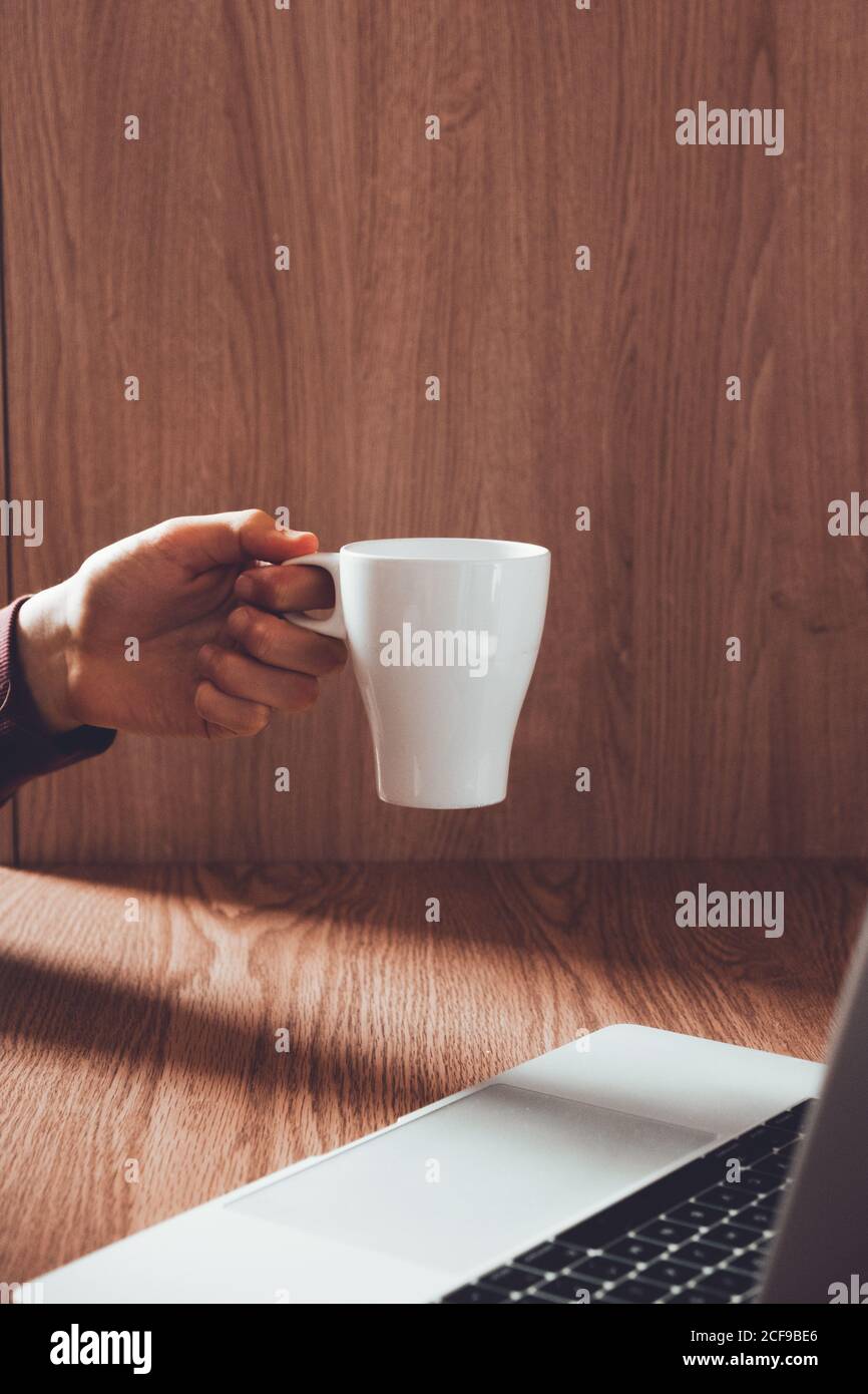 Crop man with mug using laptop Stock Photo