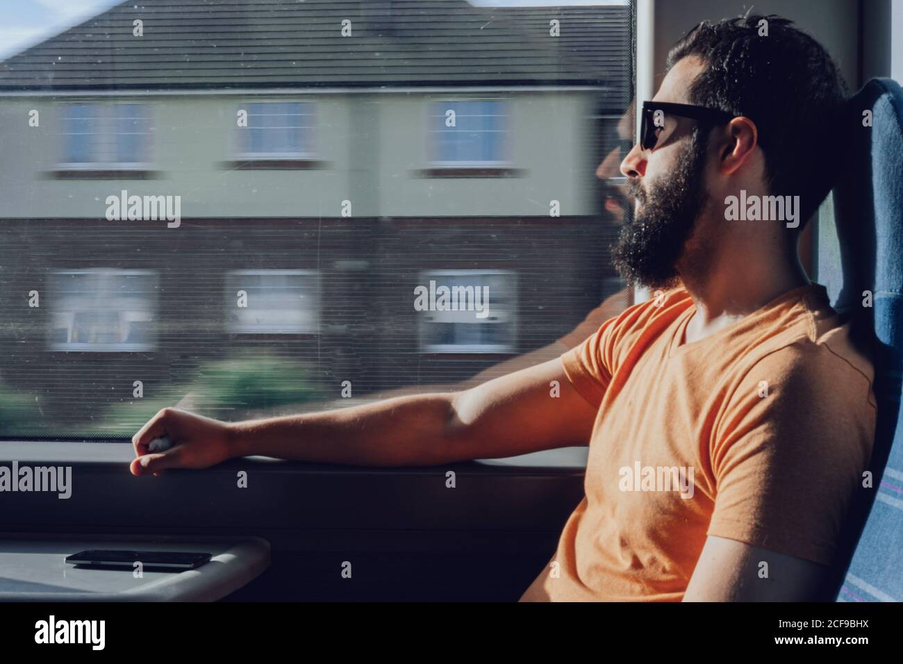 Thoughtful young bearded man looking through window while traveling by train Stock Photo