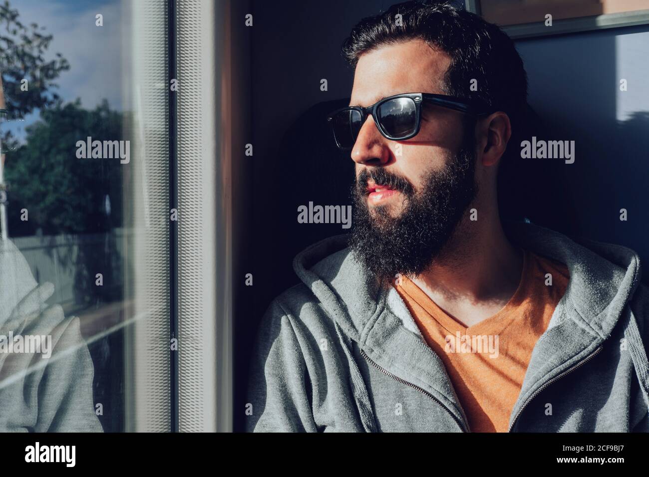 Thoughtful young bearded man looking through window while traveling by train Stock Photo