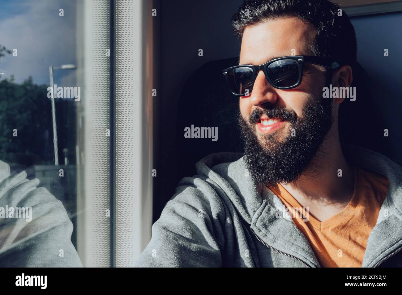 Young bearded man looking through window while traveling by train Stock Photo