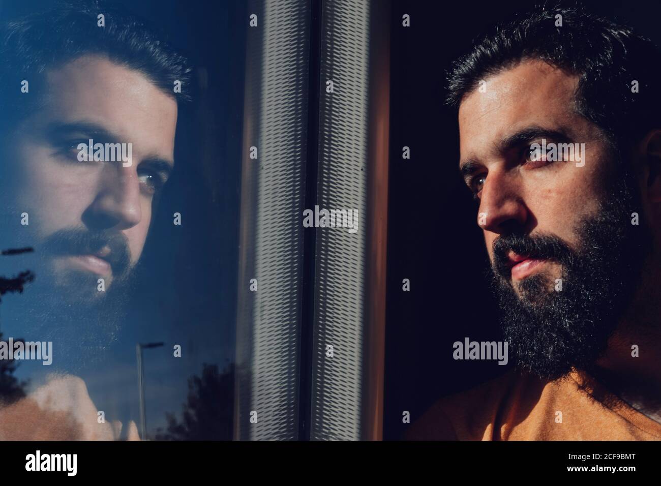 Thoughtful young bearded man looking through window while traveling by train Stock Photo