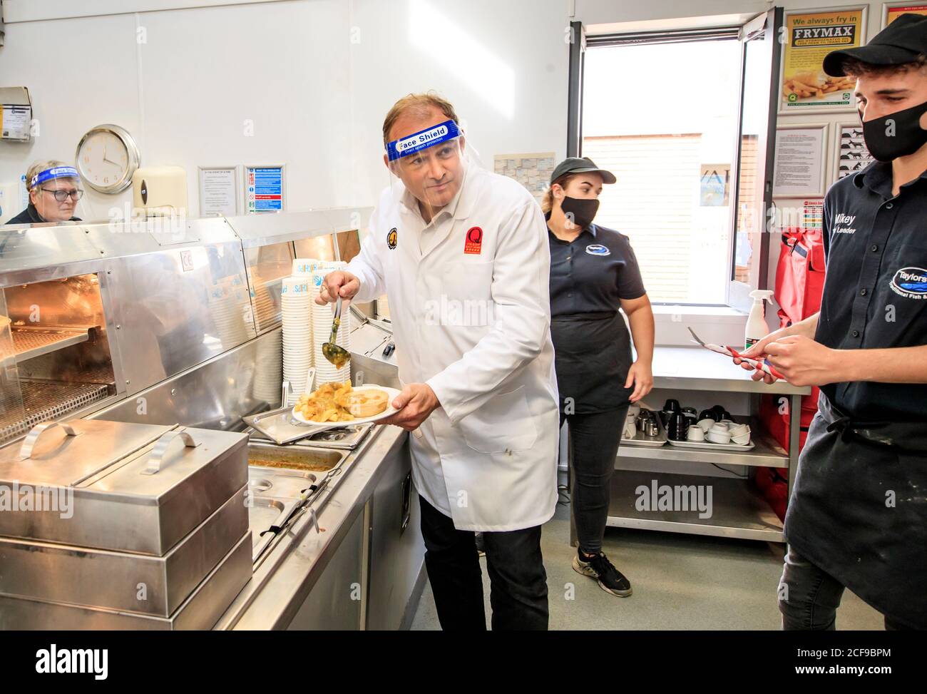 Liberal Democrat leader Ed Davey undertakes a 'shift' in Taylor's chip shop, in Stockport, during the start of his national listening tour. Stock Photo