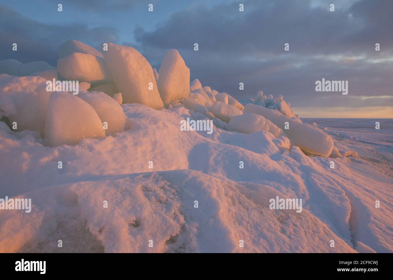 Sunset view on the winter seacoast with the stacks and piles of the ice
