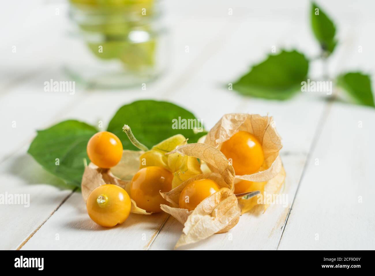 Physalis fruit (Physalis peruviana) also called uchuva, cape gooseberry or gold berries, native of Peru, on a wooden white board with leaves. Stock Photo