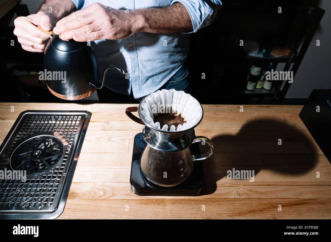 From above of anonymous male barista standing near table in cafe and preparing aromatic coffee in chemex coffeemaker Stock Photo