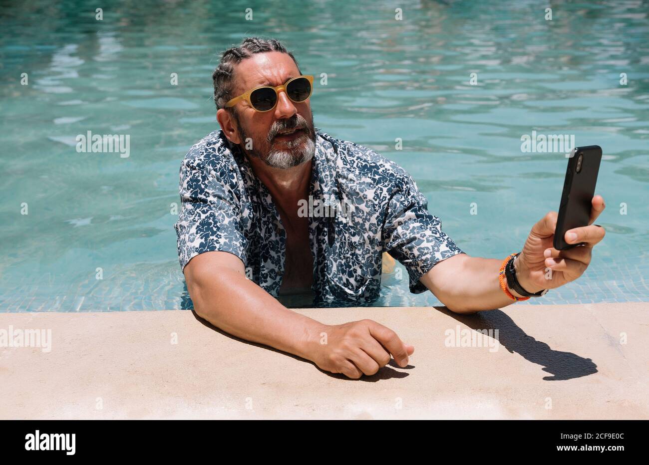 Senior man using smartphone in swimming pool Stock Photo