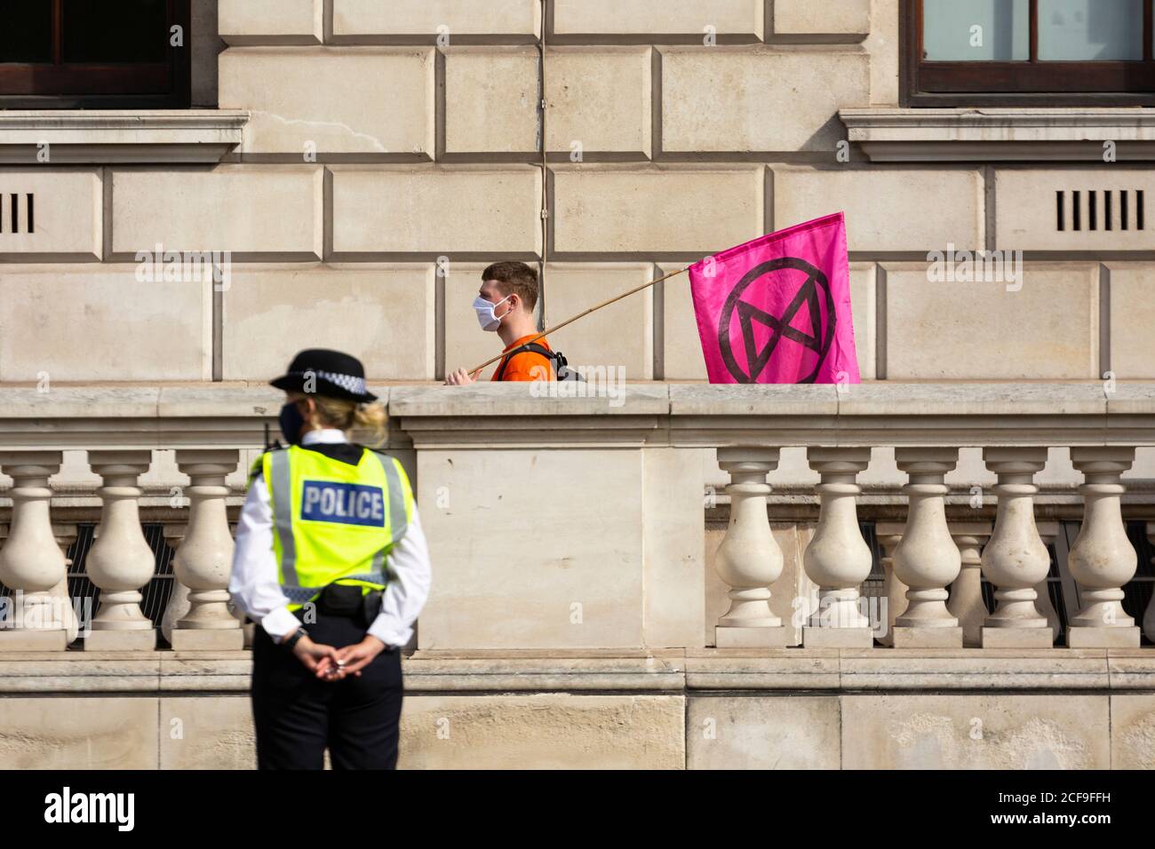 A protester with flag walks past a police officer at an Extinction Rebellion demonstration, Parliament Square, London, 2 September 2020 Stock Photo