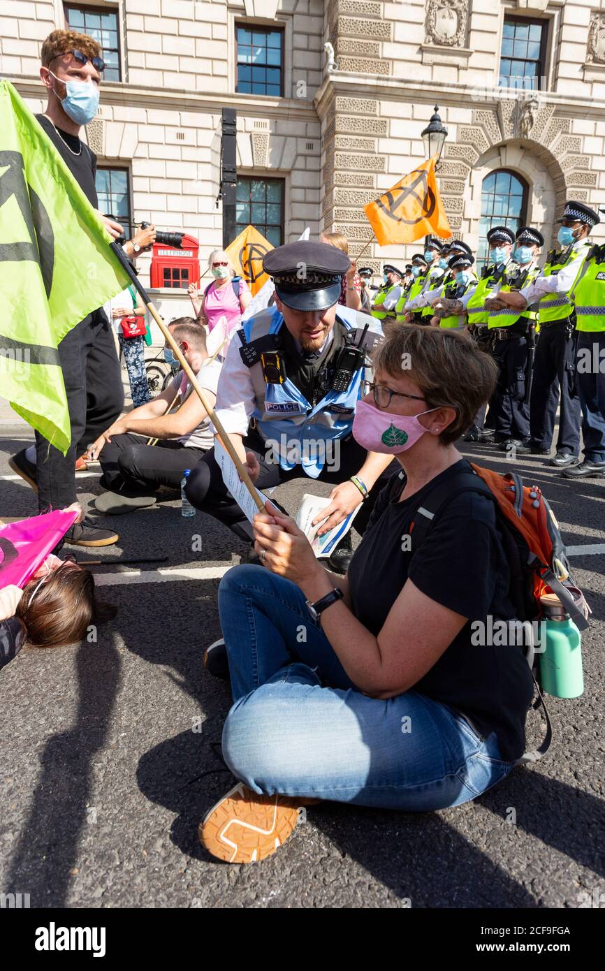 A police officers talks to a protester blocking road, Extinction Rebellion demonstration, Parliament Square, London, 2 September 2020 Stock Photo