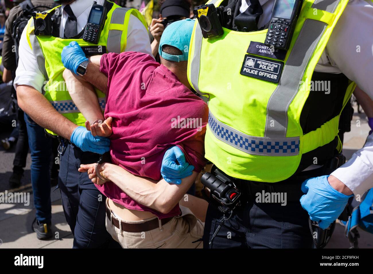 Police carry off an arrested man in handcuffs, Extinction Rebellion