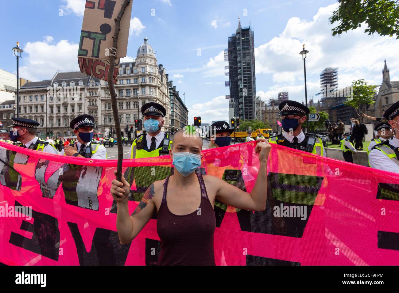 A protester holding banner with police behind, Extinction Rebellion demonstration, Parliament Square, London, 2 September 2020 Stock Photo