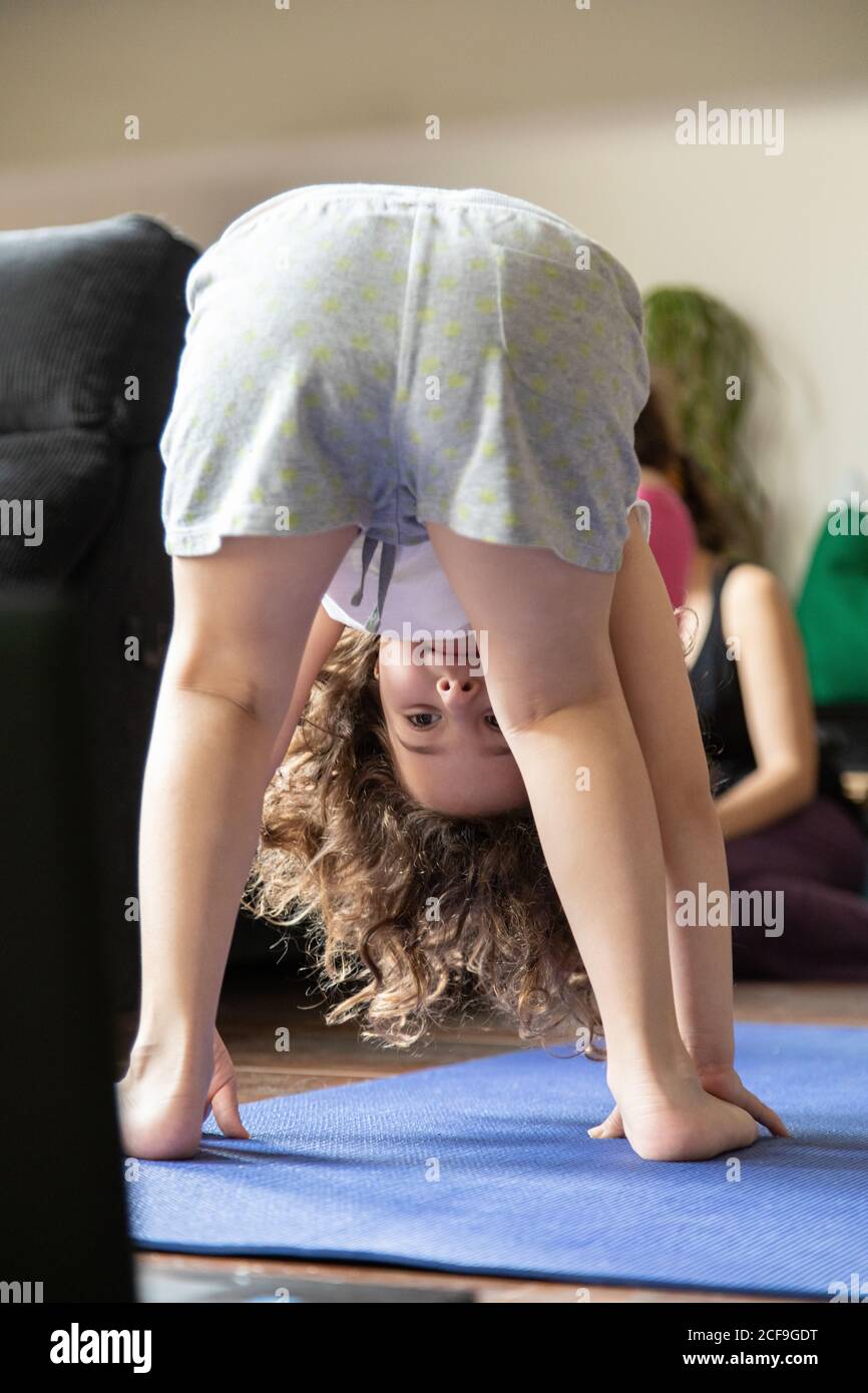 Back view of unrecognizable little girl watching online video tutorial on  laptop while sitting on mat and learning yoga pose at home Stock Photo -  Alamy