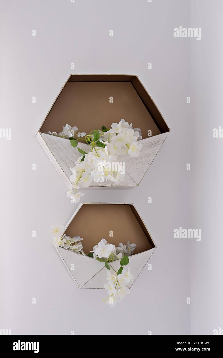 Hexagonal decorative flower storage shelf on white wall. Wedding decor Stock Photo