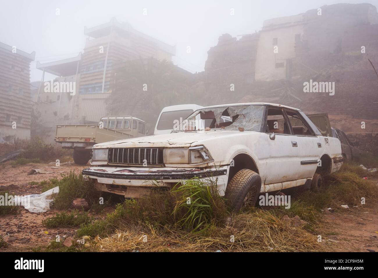 Vehicle with shattered windshield located on junkyard on misty day on