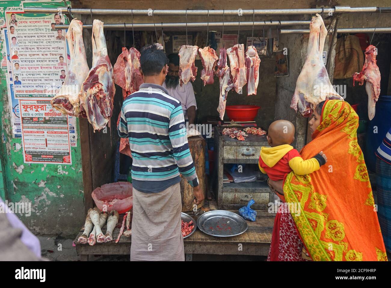 Back view of ethnic man and Woman with child in traditional clothes buying meat from butcher shop in Barisal in Bangladesh Stock Photo