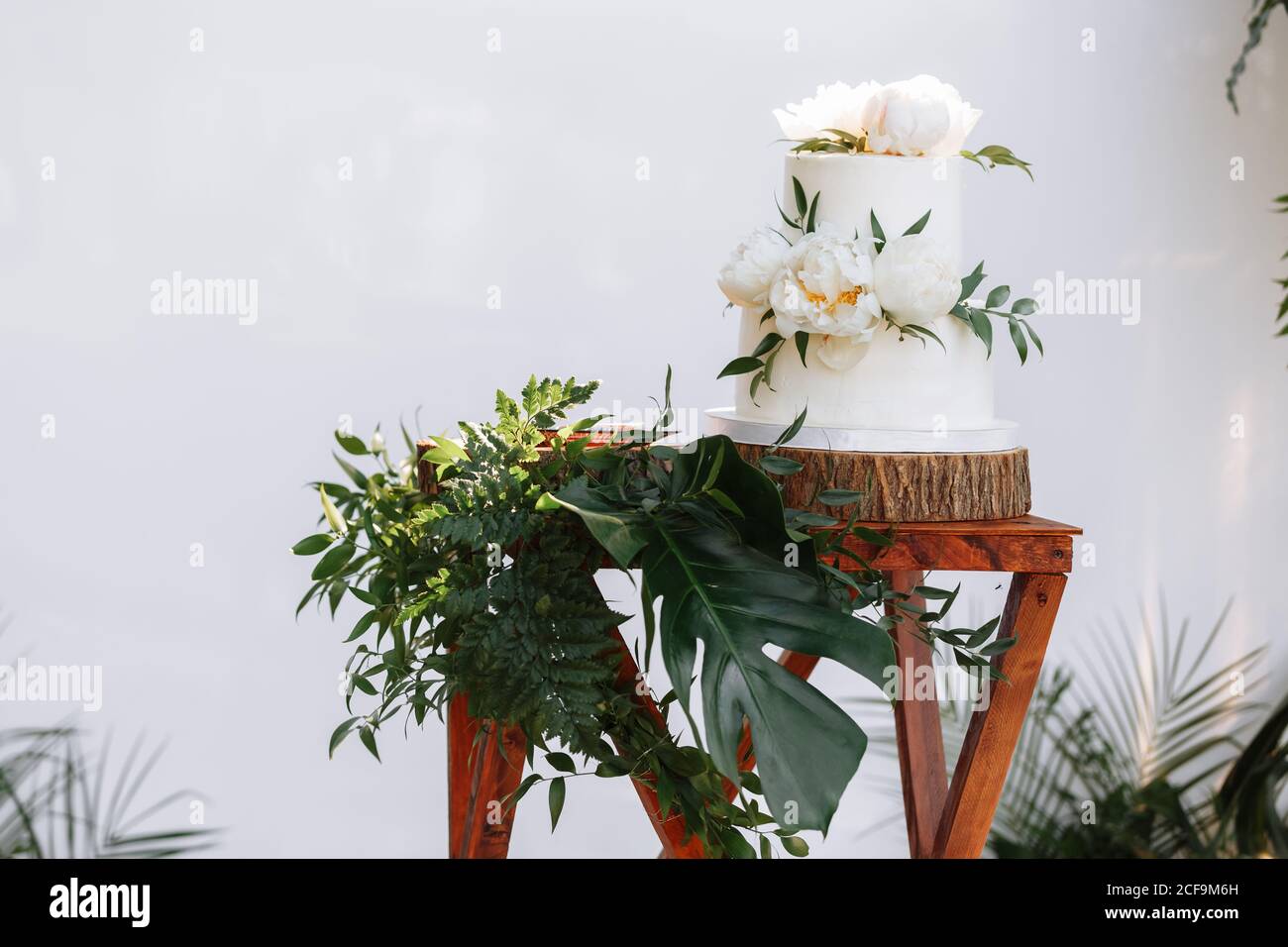 Elegant wedding cake with flowers and succulents. Two-tiered white wedding cake with floral on a wooden table Stock Photo