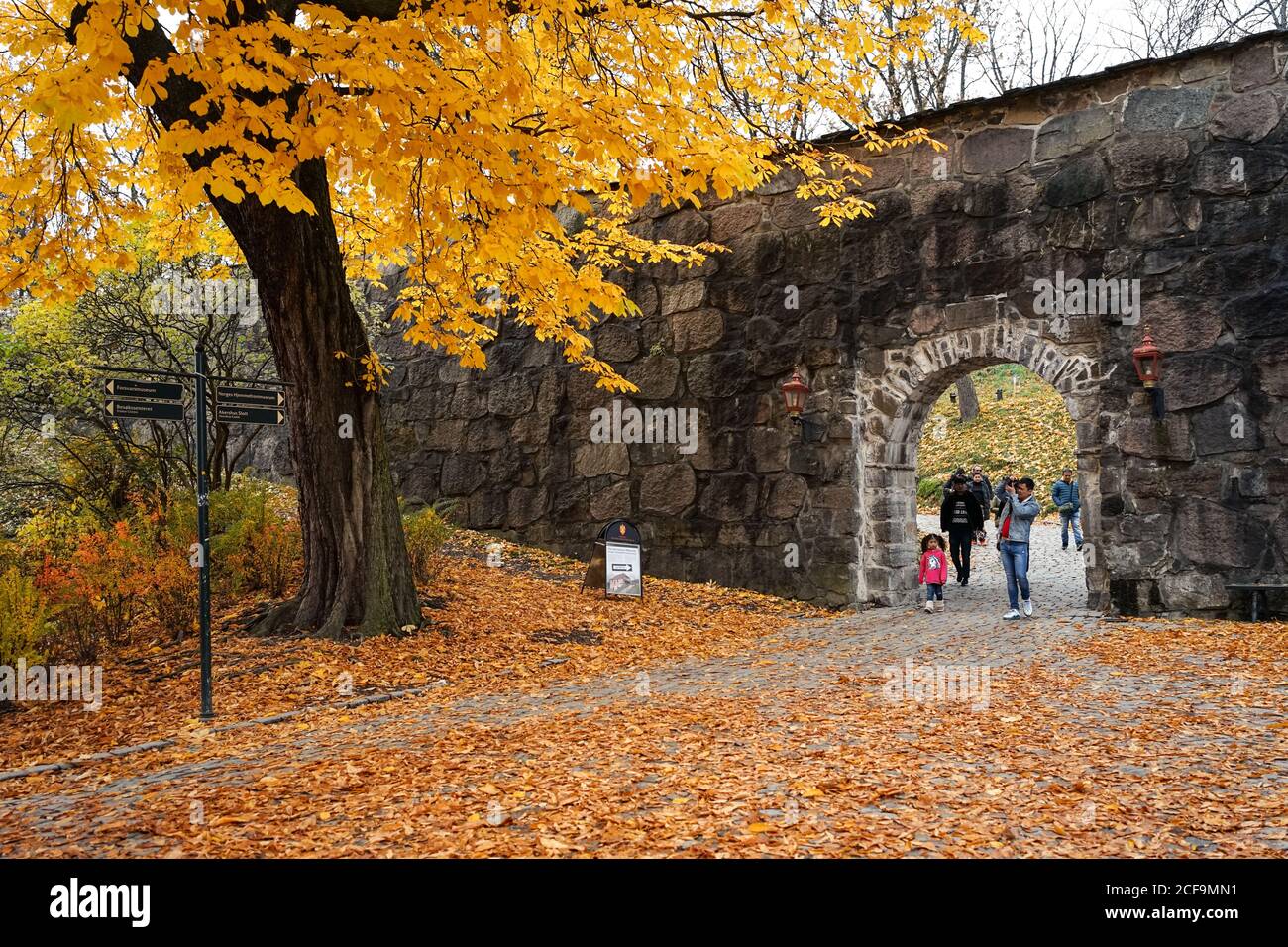 Group of travelers walking into patio of Oslo Cathedral during sightseeing in golden autumn in Norway Stock Photo