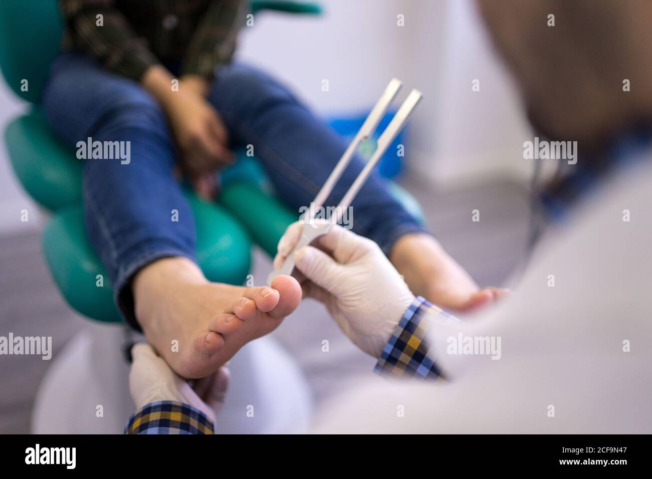 Crop male podiatry doctor using professional medical instrument while treating foot of female patient in modern clinic Stock Photo