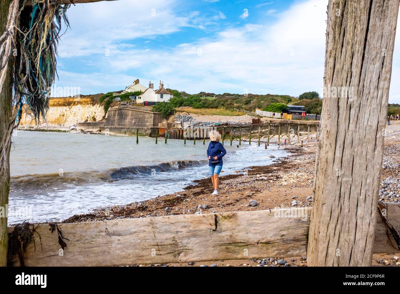 Seaford UK 04 September 2020 - A walker enjoys the warm sunny day with a mix of clouds at Cuckmere Haven near Seaford on the Sussex coast today with the famous coastguard cottages perched on the cliffs which are gradually eroding away  . : Credit Simon Dack / Alamy Live News Stock Photo