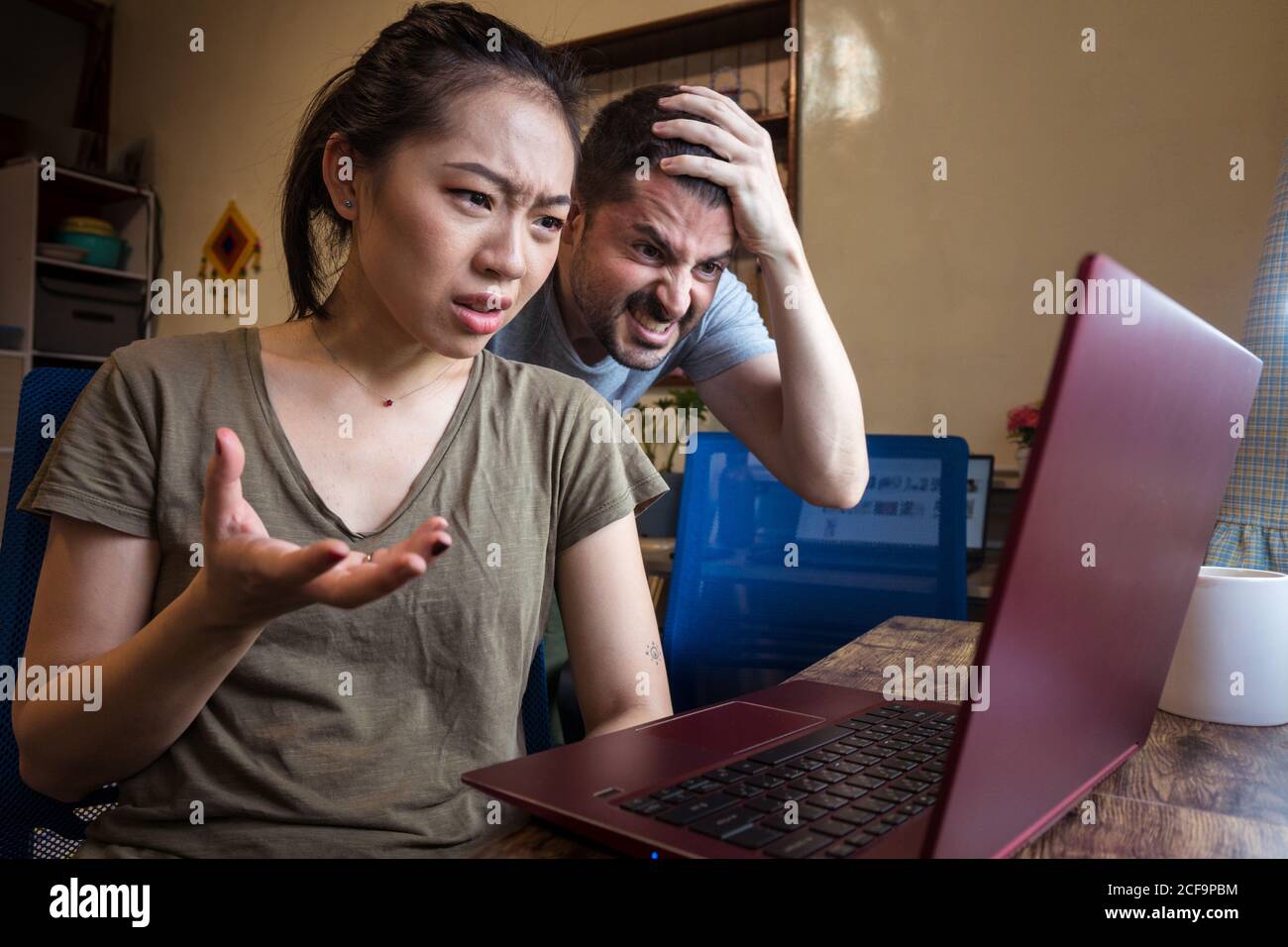 Low angle of multiethnic couple having problems with computer while working together on project online Stock Photo