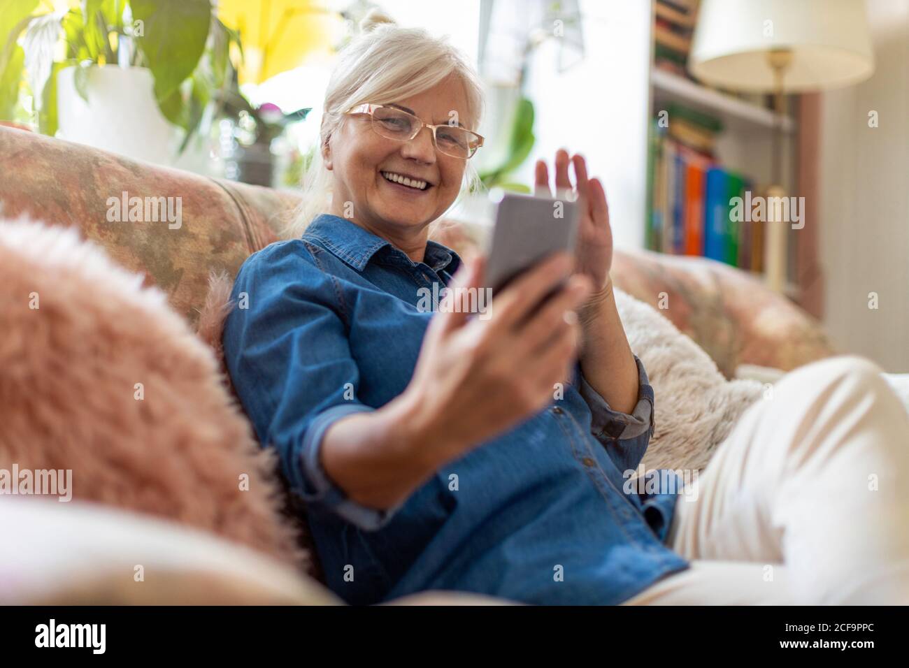 Senior woman using mobile phone at home Stock Photo