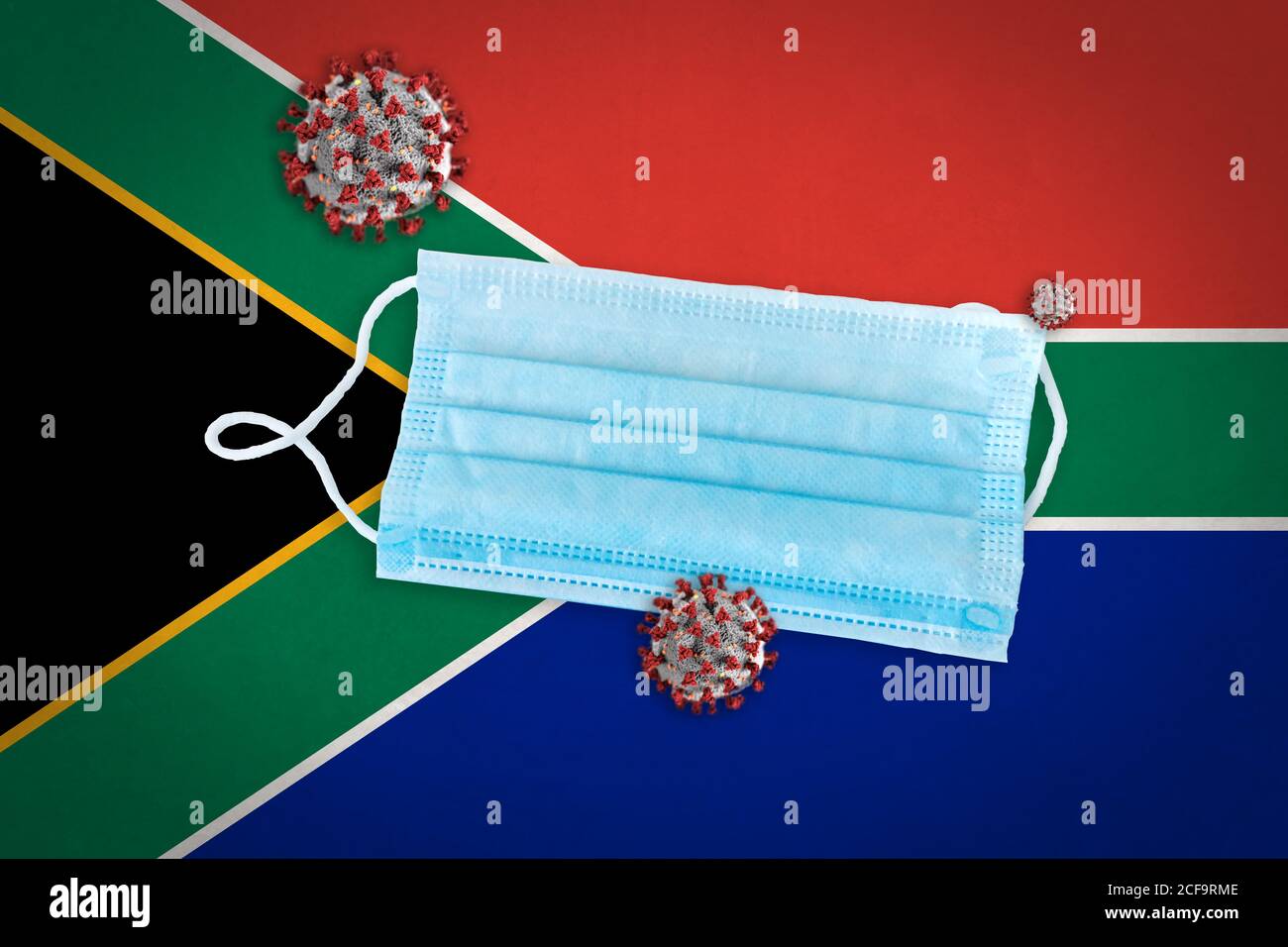 Concept of Coronavirus or Covid-19 particles and surgical face mask over flag of South Africa in background. Stock Photo