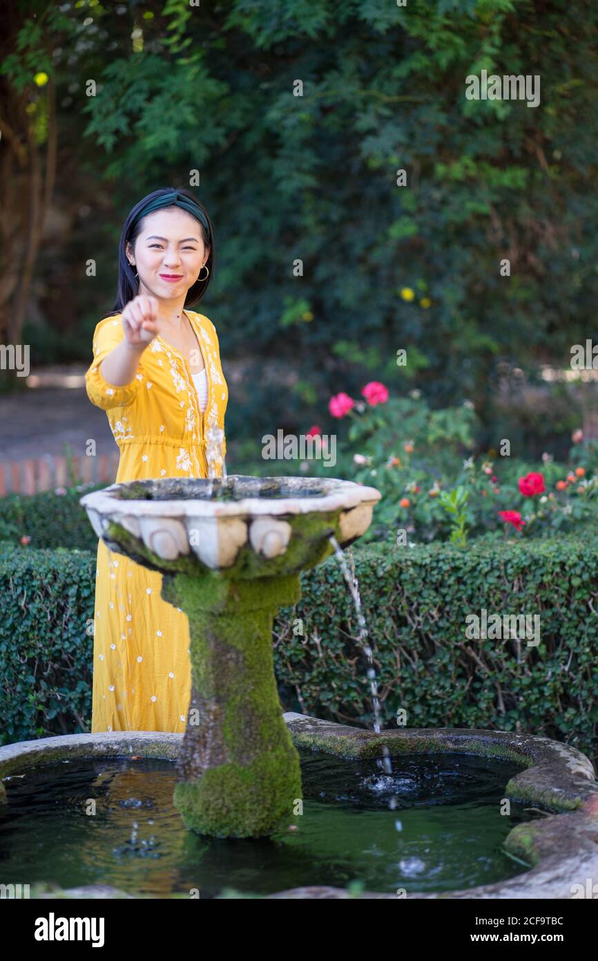 Asian Woman touching fountain water in garden Stock Photo - Alamy