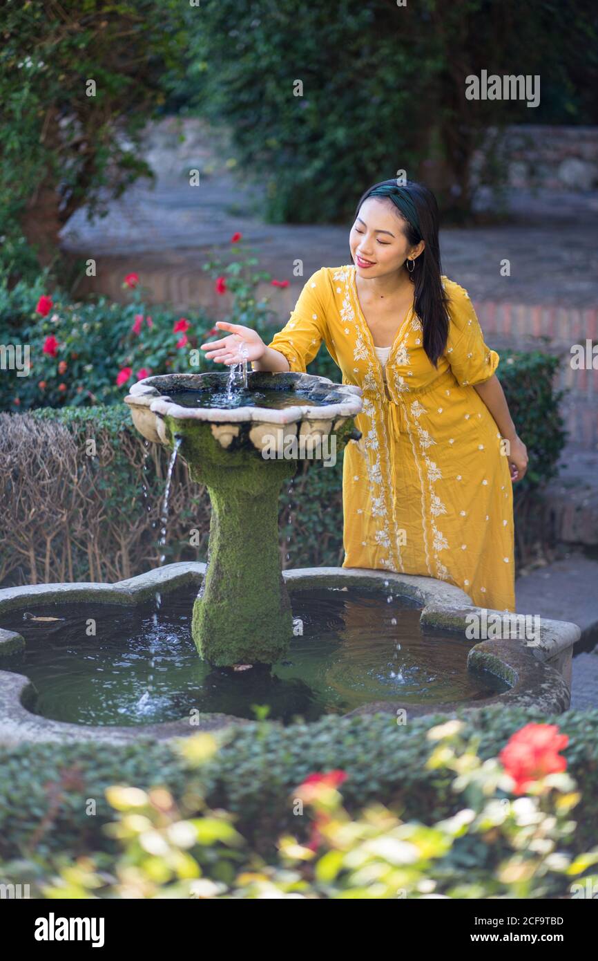 Asian Woman touching fountain water in garden Stock Photo - Alamy