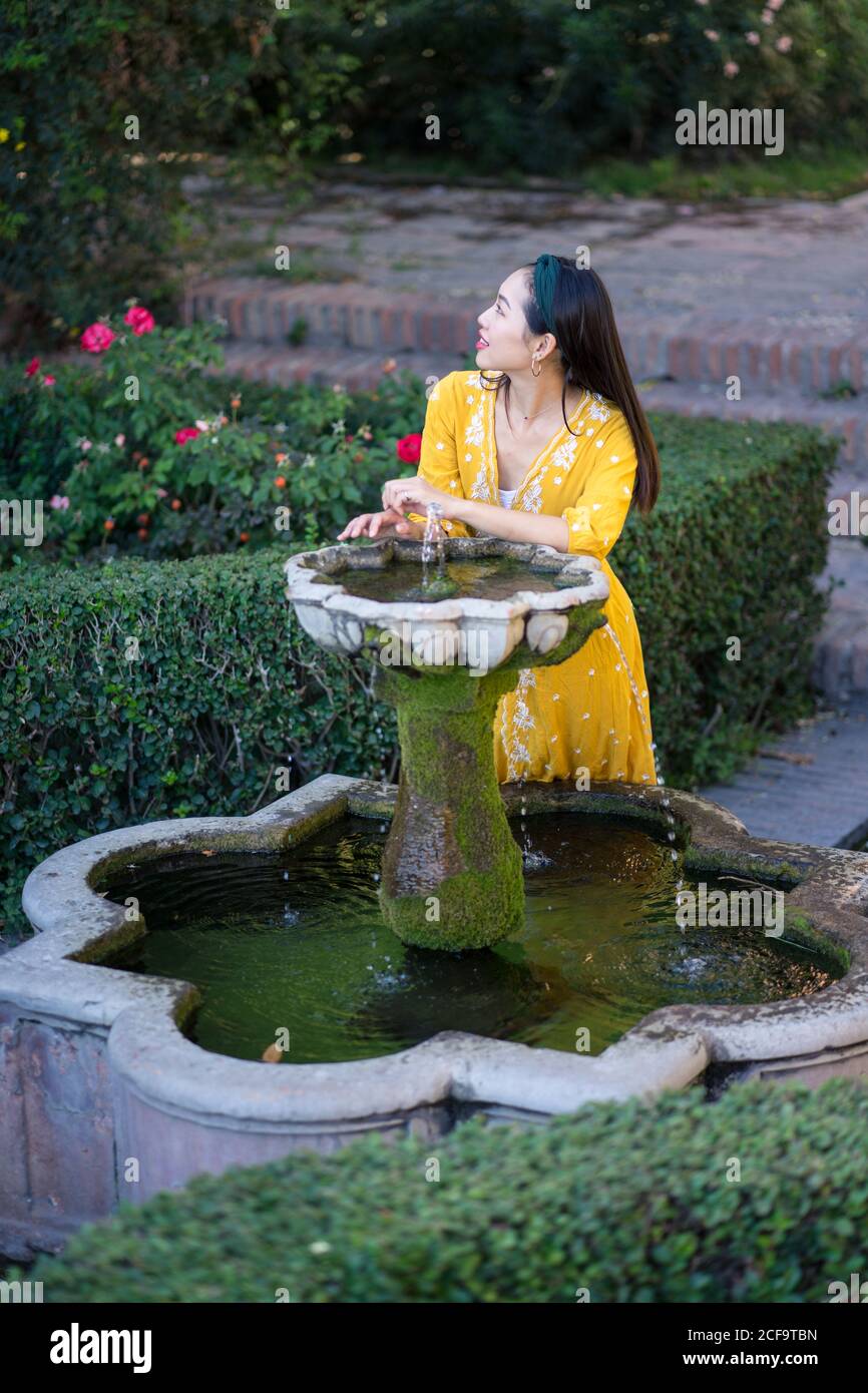 Asian Woman touching fountain water in garden Stock Photo - Alamy