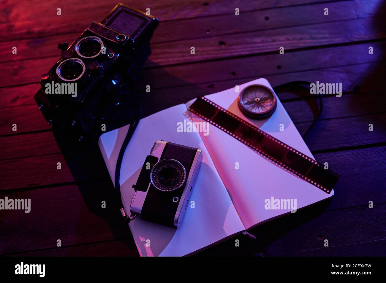 From above top view of black retro photo camera with notebook and film composed with vintage radio on wooden table in dark studio Stock Photo