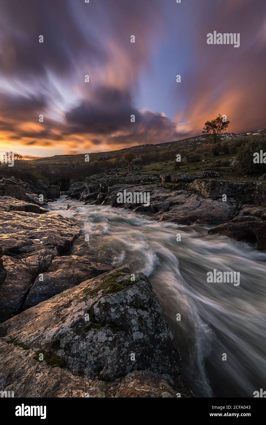 Picturesque view of mountain river streaming through rocky cliffs in calm evening during sunset in autumn Stock Photo
