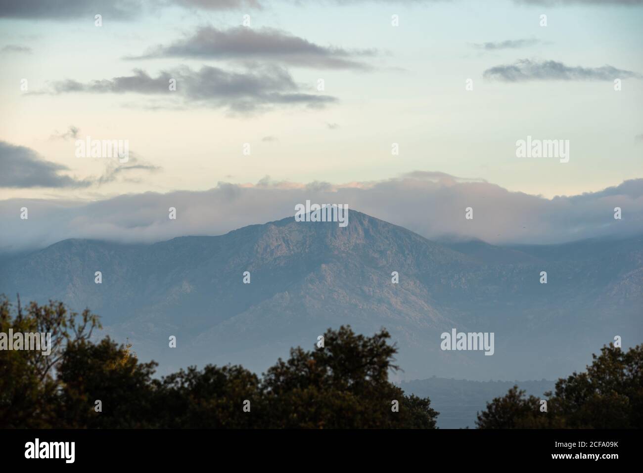 Calm landscape with mountain range covered with fog against cloudy morning sky in autumn season Stock Photo