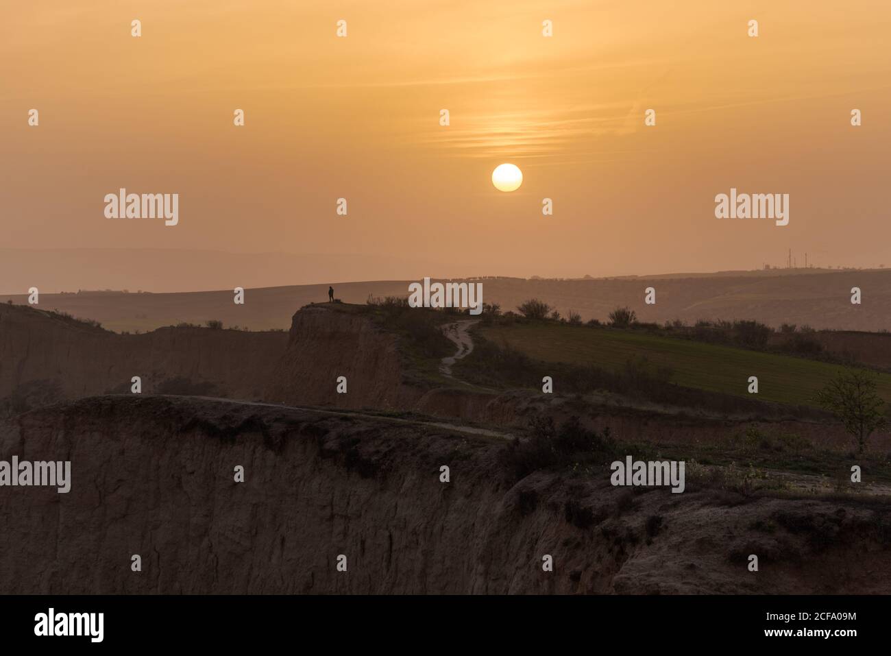 Amazing mountain landscape with silhouette of unrecognizable person against cloudy sundown sky Stock Photo