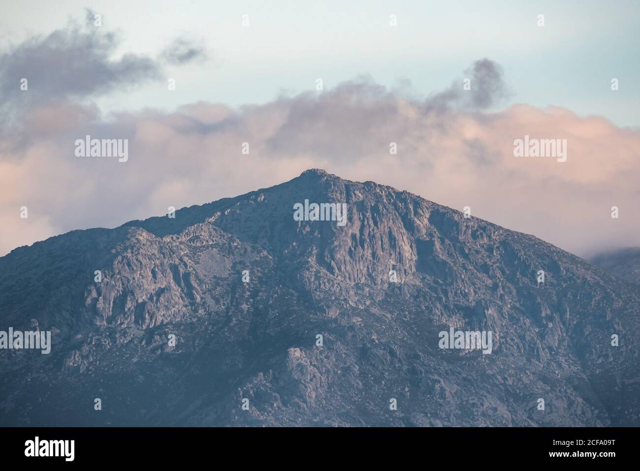 Calm landscape with mountain range covered with fog against cloudy morning sky in autumn season Stock Photo