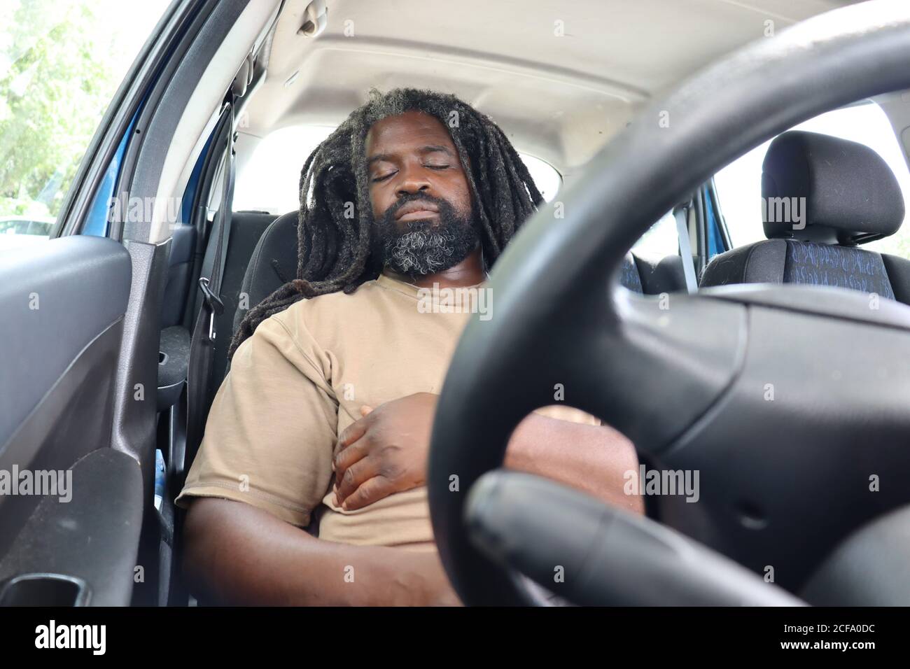 Tired driver resting on long journey. Man sleeps in car for a break. Stock Photo