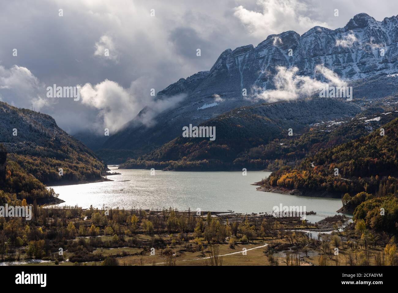 Lake close to snowy mountain ridge and cloudy sky in a landscape autumn Stock Photo
