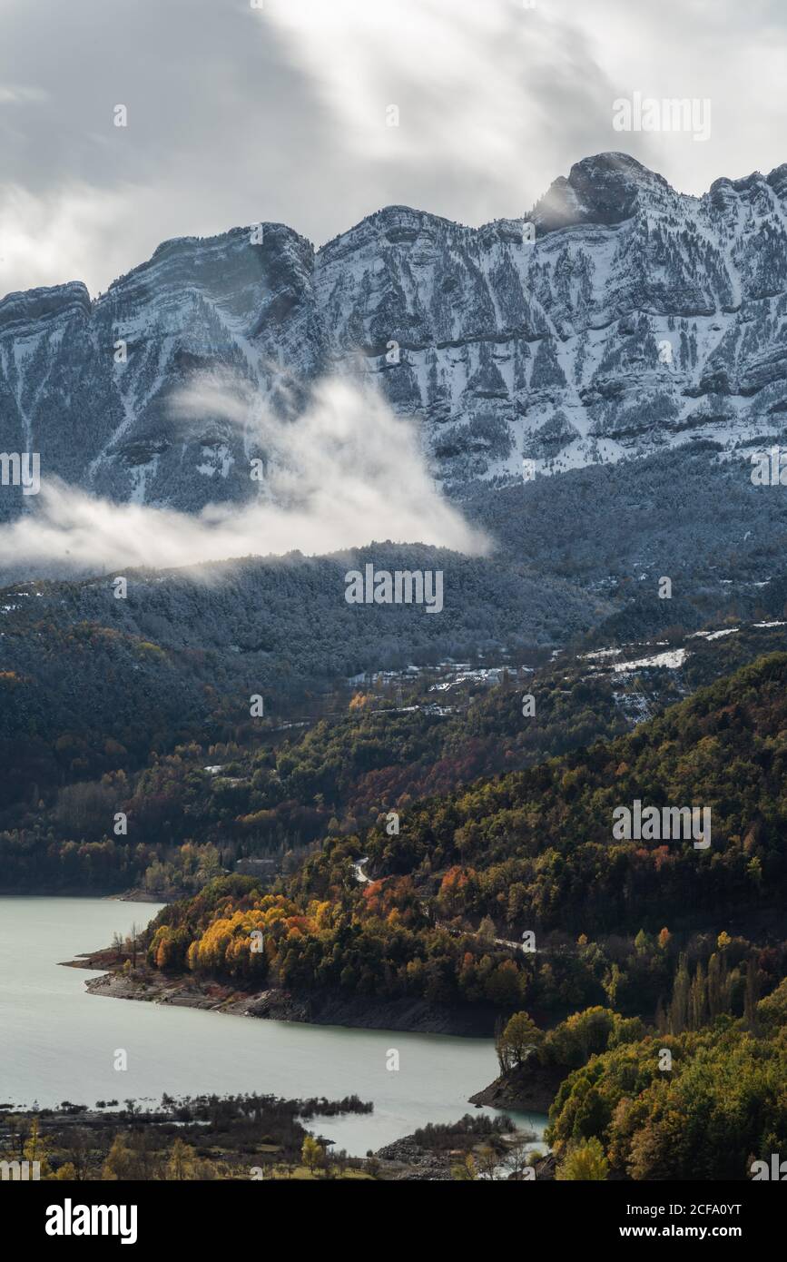 Lake close to snowy mountain ridge and cloudy sky in a landscape autumn Stock Photo