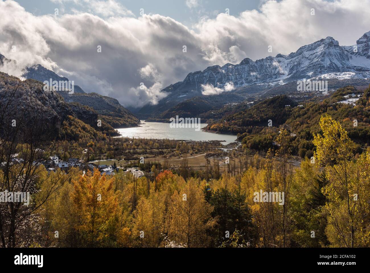 Lake close to snowy mountain ridge and cloudy sky in a landscape autumn Stock Photo