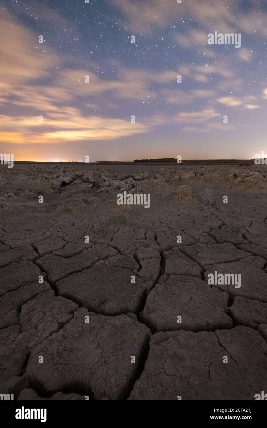 Drought cracked lifeless ground under colorful cloudy sky at sunset time Stock Photo