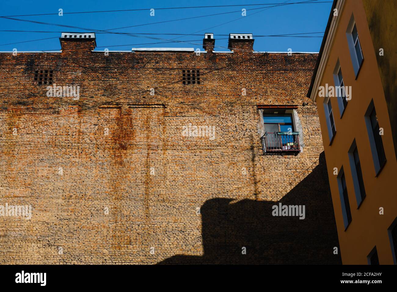 Brick firewall with one window in inner yard, old building with firewall on sunny day Stock Photo