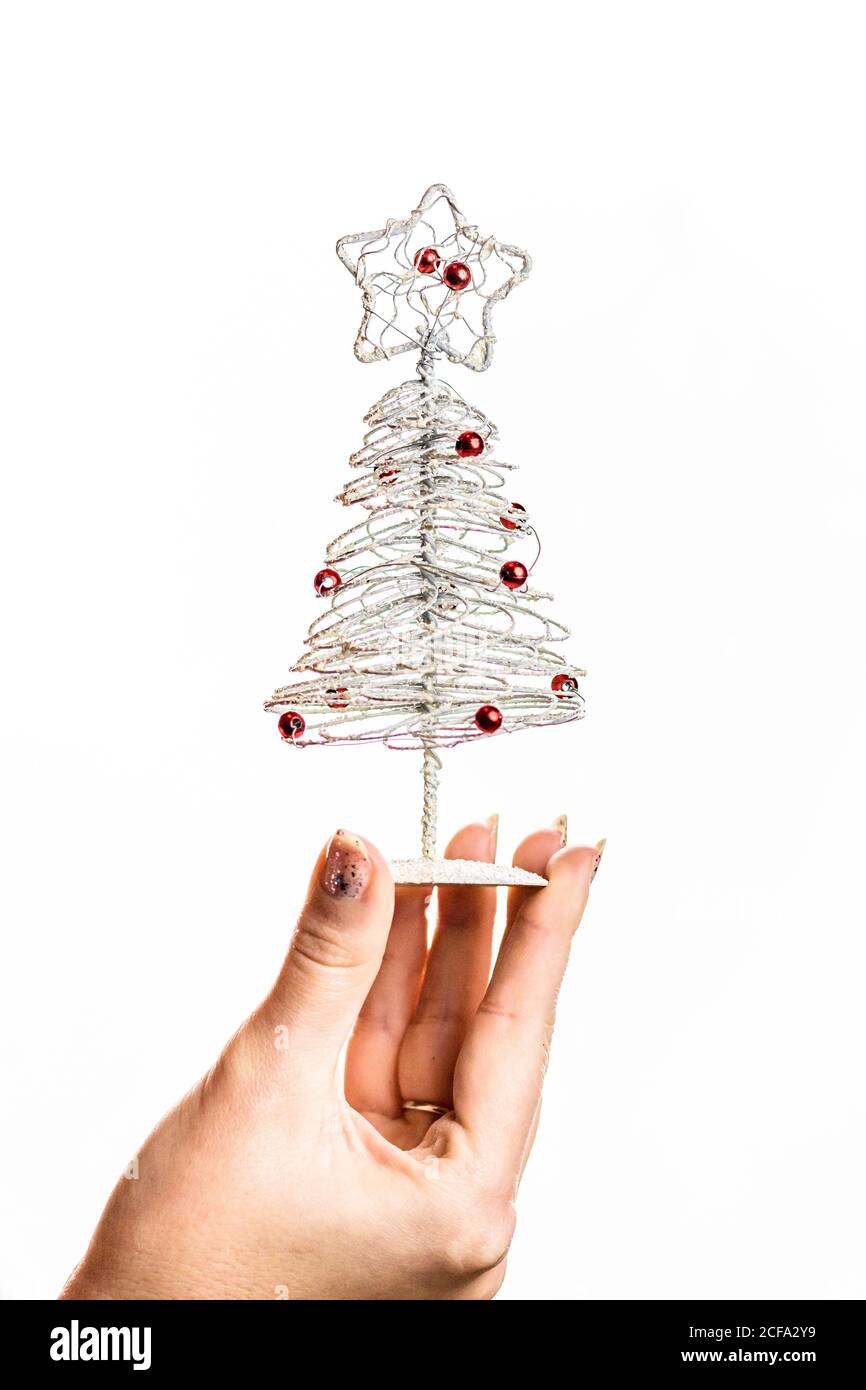 Hand holding small silver wire Christmas tree isolated on white