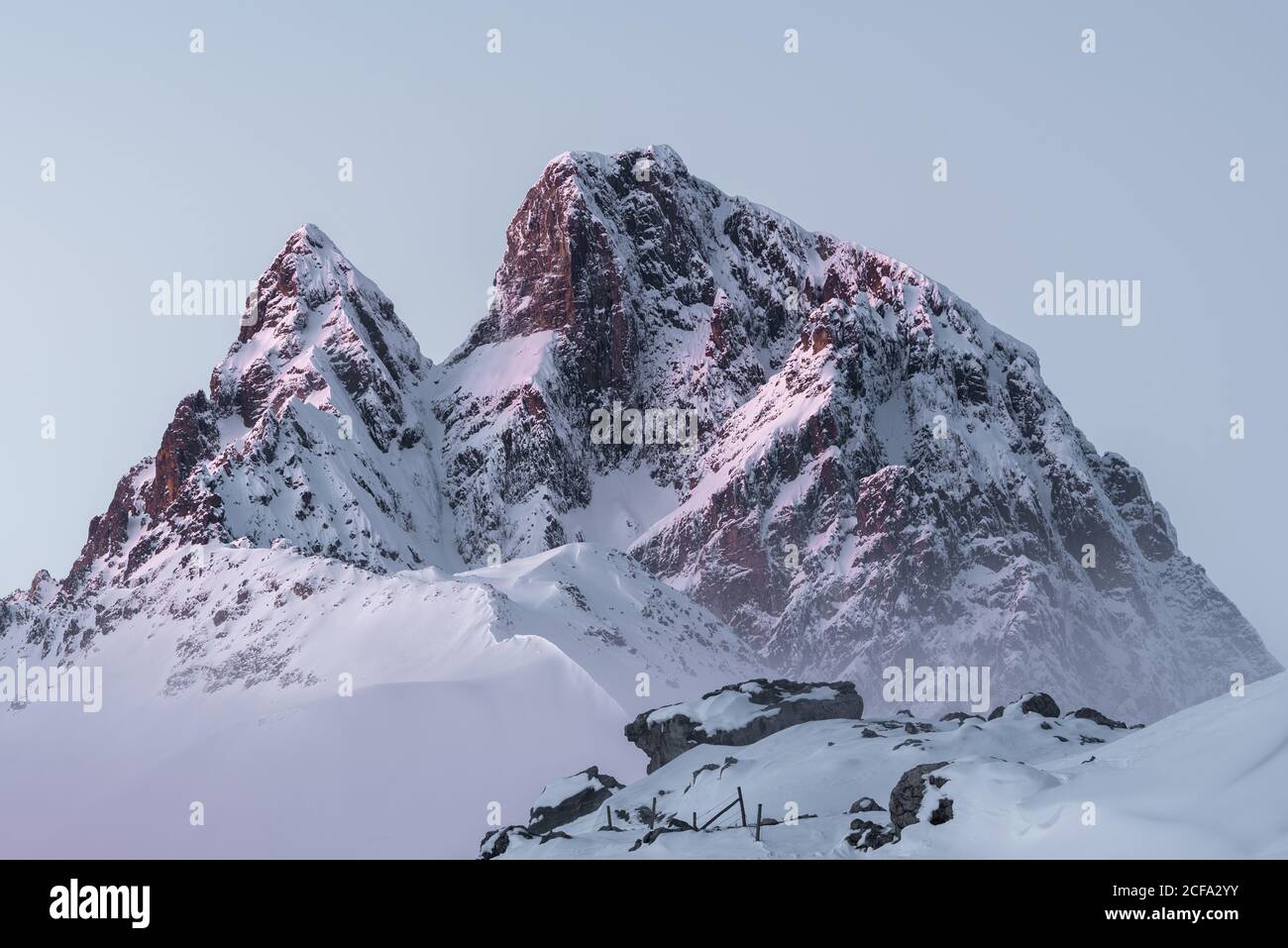 Sharp mountain peaks covered partially with snow under cloudy sky in wintertime Stock Photo