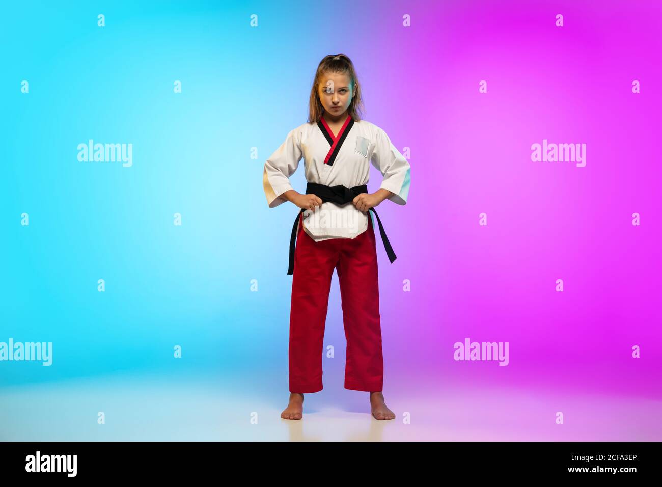 Powerful. Karate, taekwondo girl with black belt isolated on gradient