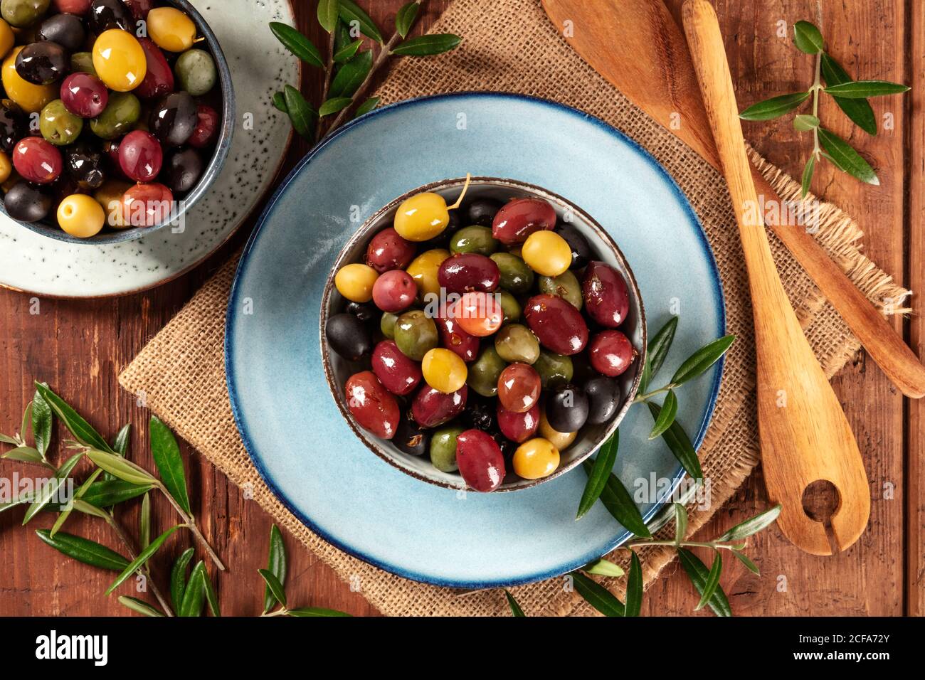 Olives. A variety of green, black and red olives, with leaves, shot from the top on a rustic wooden background Stock Photo
