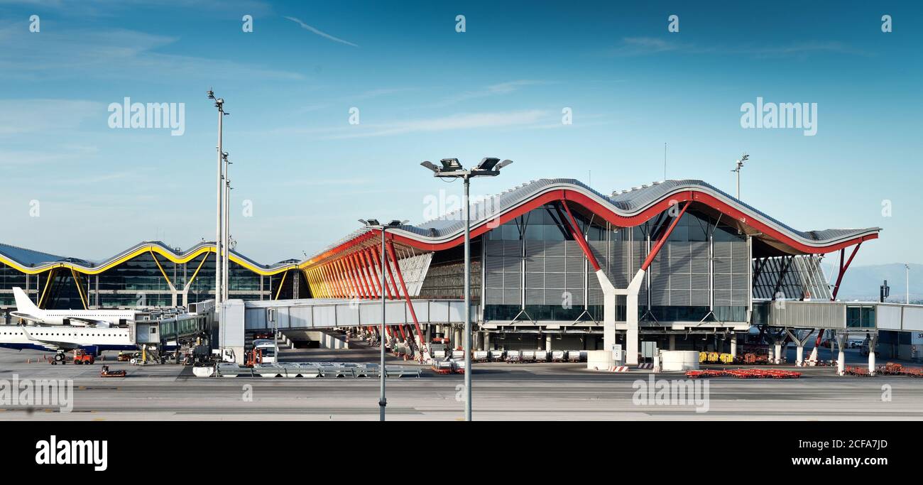 Unusual facade of Madrid Barajas airport with wavy roof and vivid yellow pillars in composition with window walls under blue sky in Spain Stock Photo