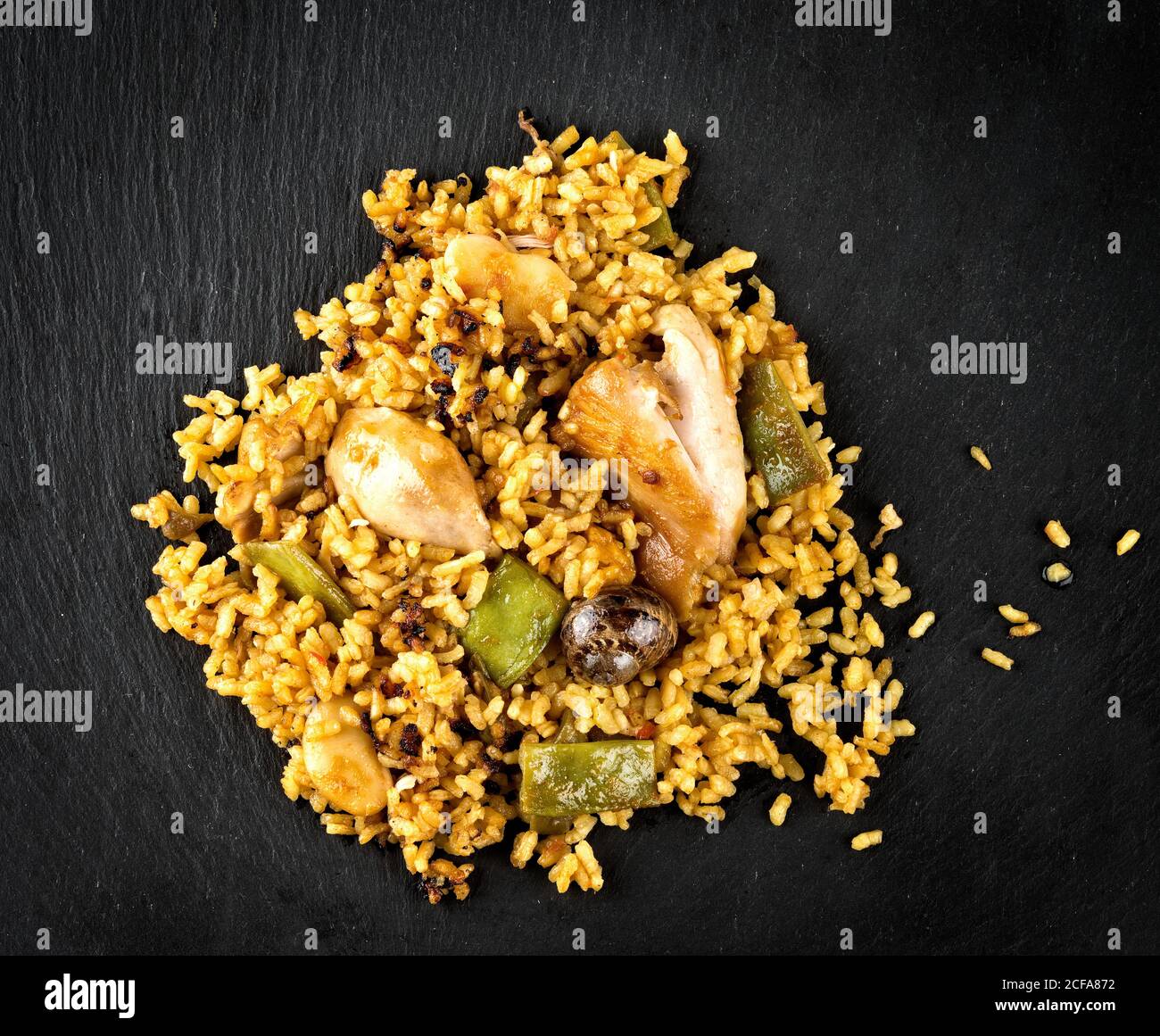 Top view of appetizing spicy Spanish paella with chicken and seafood served on black slate board Stock Photo