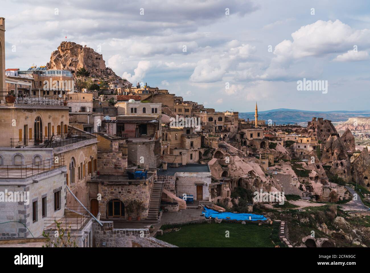 Shabby stone houses of old city located on rough mountain against cloudy sky of Cappadocia, Turkey Stock Photo